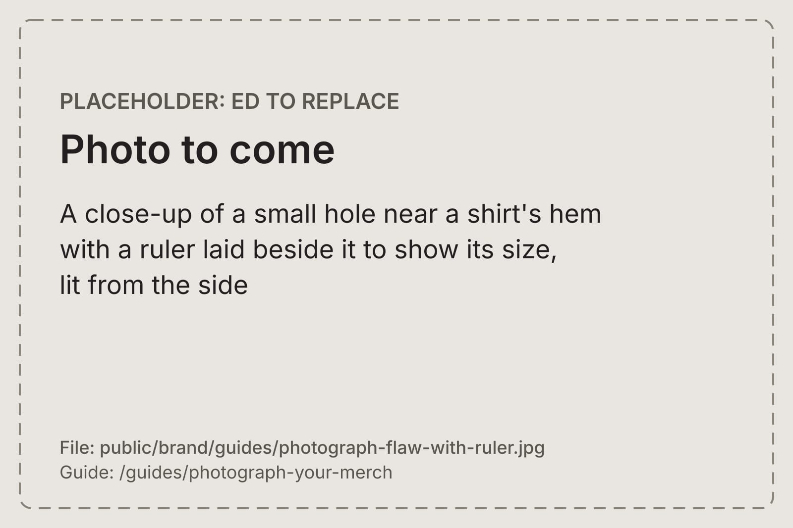 A close-up of a small hole near a shirt's hem with a ruler laid beside it to show its size, lit from the side