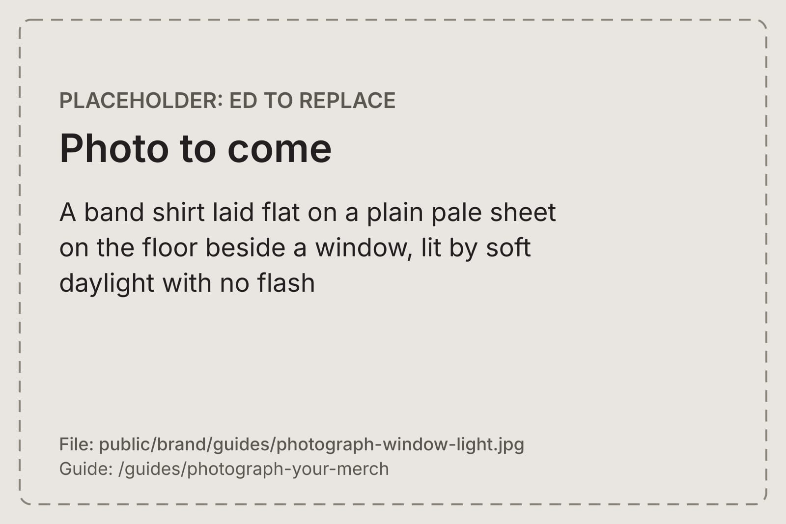 A band shirt laid flat on a plain pale sheet on the floor beside a window, lit by soft daylight with no flash
